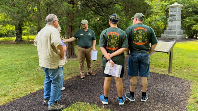An intern giving a talk outside to a group of 5 people.