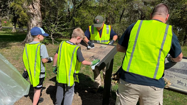 Volunteers cleaning an interpretive sign at the park.
