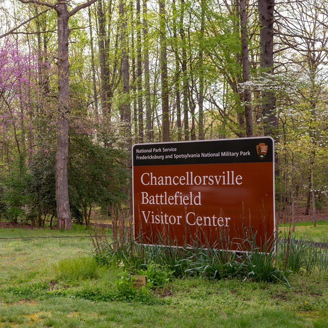 Brown park sign for Chancellorsville Visitor Center with spring flowers