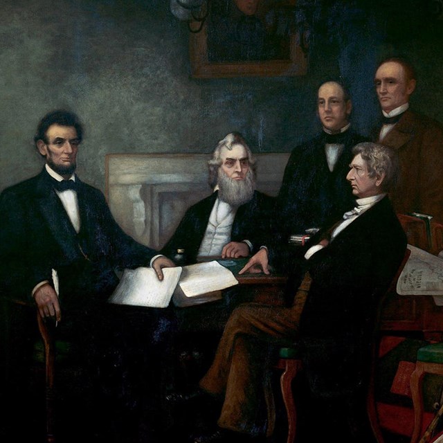 A painting of men in suits standing around a seated Abraham Lincoln.