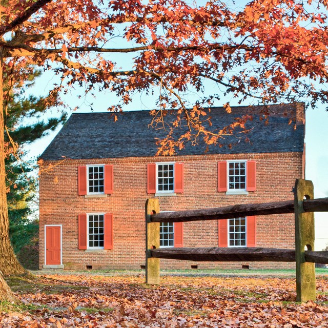 Fall photo through a wooden fence of a two story brick church.