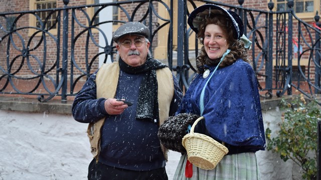 A man and a woman in historic clothing pose for a photo. 