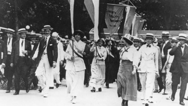 Women holding banners marching down the street 