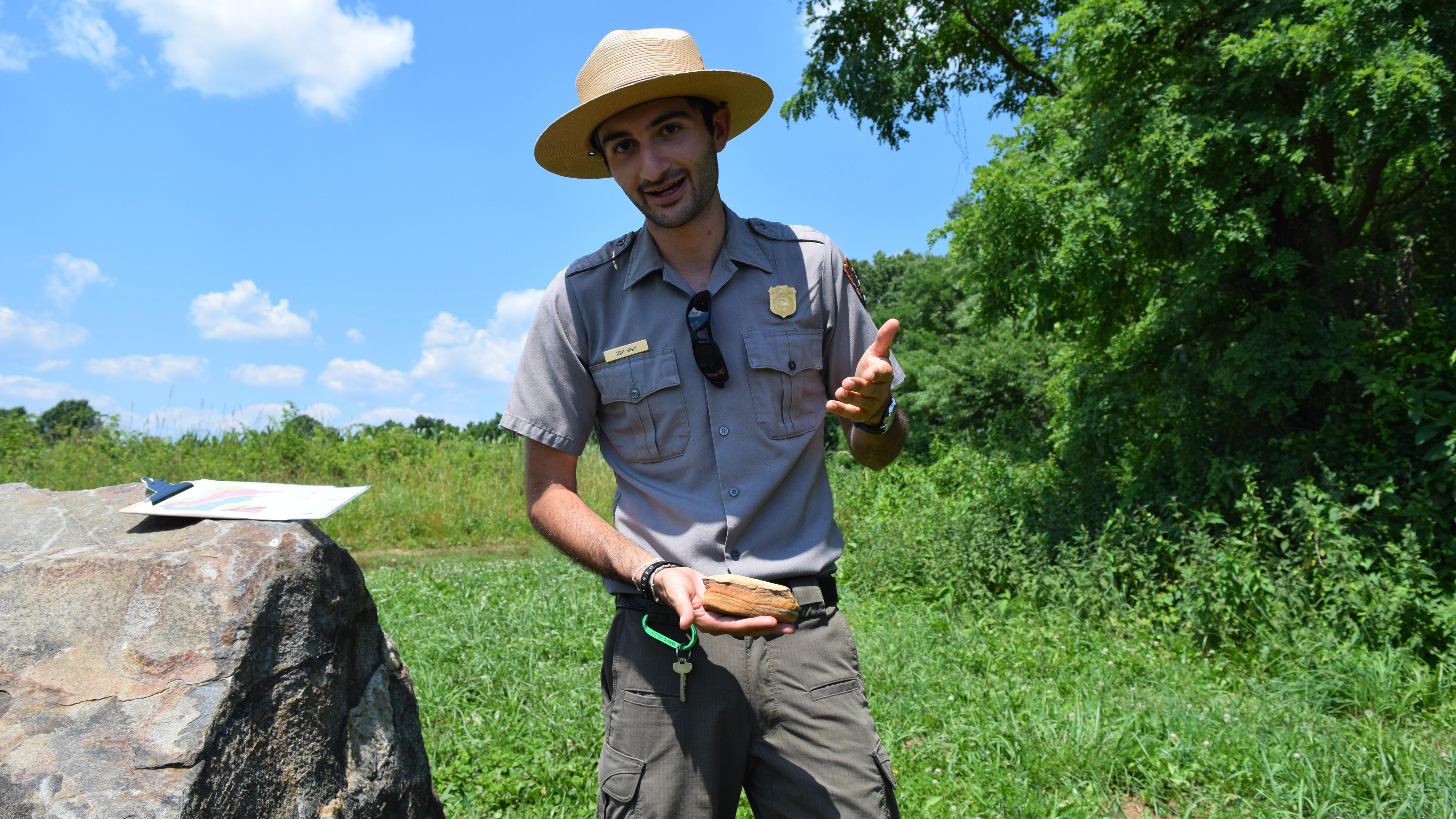 A male Park Ranger provides talks about rocks outside
