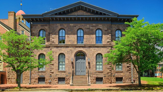 A two-story brick Italianate building with large gray double doors.