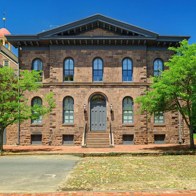 A two-story brick Italianate building with large gray double doors.