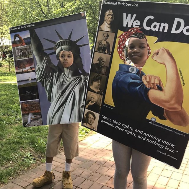 A photo of two kids pretending to be the Statue of Liberty and Rosie the Riveter 