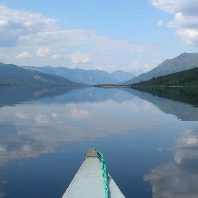 View from a canoe looking at clear and calm Walker Lake; mountains are reflected in the lake's water