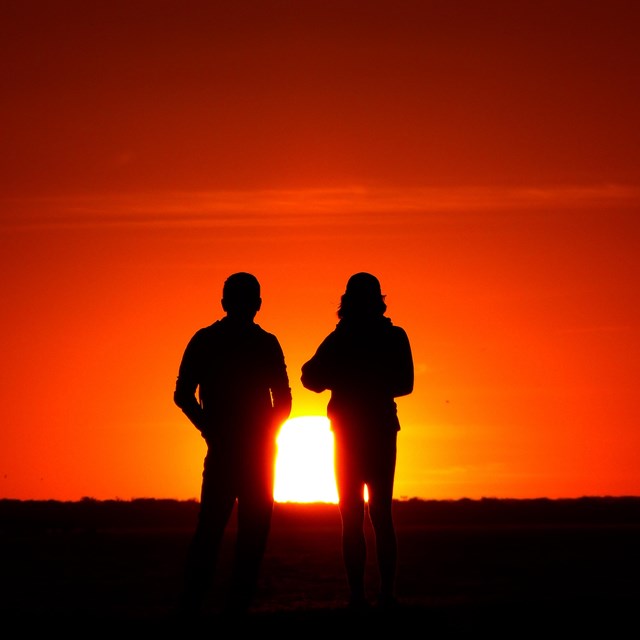 Two people silhouetted in front of a sunset