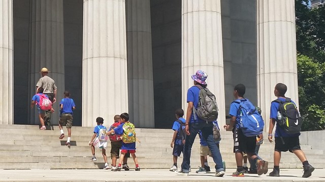 Ranger and students walking up steps in front of large columns of Mausoleum