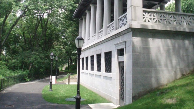 A granite building with an overlook pavilion on top. There is a greenery surrounding the building.