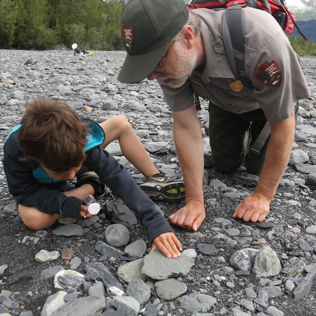 ranger and youth examining rocks in gravel bar