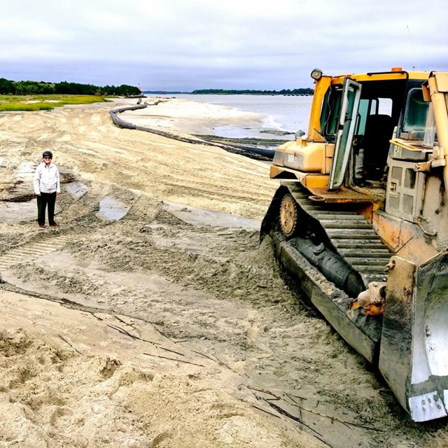 heavy equipment spreading sand on a beach