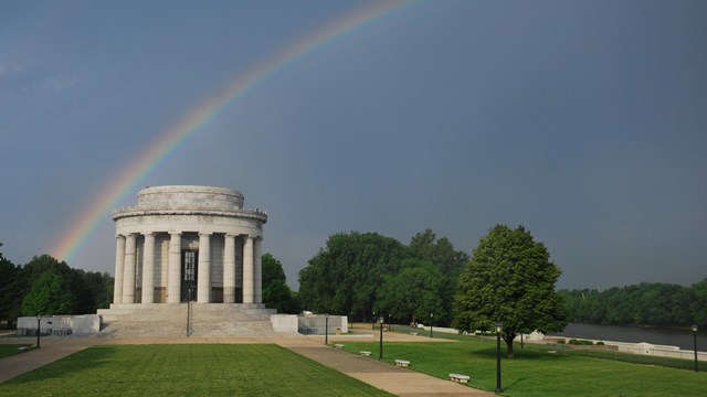 The Clark Memorial building under a cloudy sky and rainbow