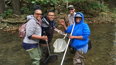 Group of volunteers standing in a creek holding gear for scientific research 