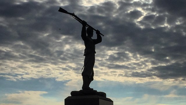 The 72nd Pennsylvania infantry monument is silhouetted against gray clouds.