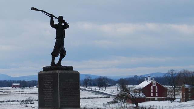 A stone and metal monument stands in the snow