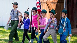 A park ranger marches with students at one of the historic homes on the battlefield.