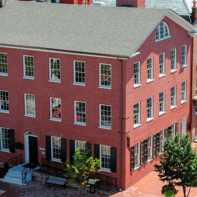 Historical red brick building with many rows of windows on left and right side of the home.