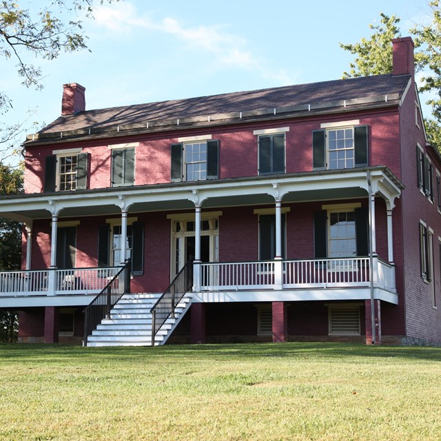 Historic two story red home with white steps and white front porch.