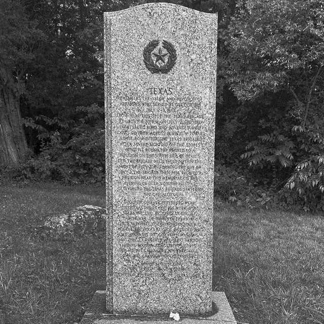A black and white photo of a vertical monument from the state of Texas with a Texas star at the top.