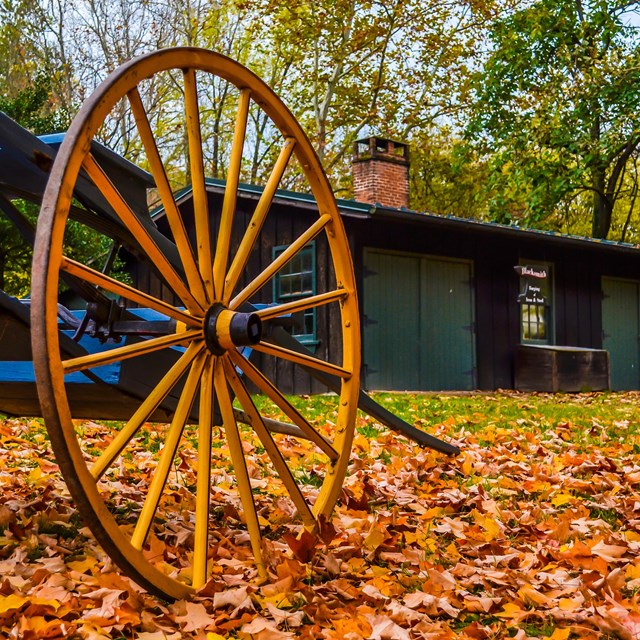 A hand cart rests among the fall leaves next to the Blacksmith Shop in Lower Town