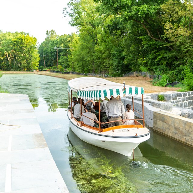 A small boat with a green and white striped tarp in a canal. 