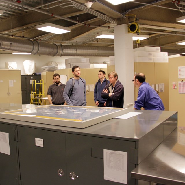 A group of people stand around a large filing cabinet