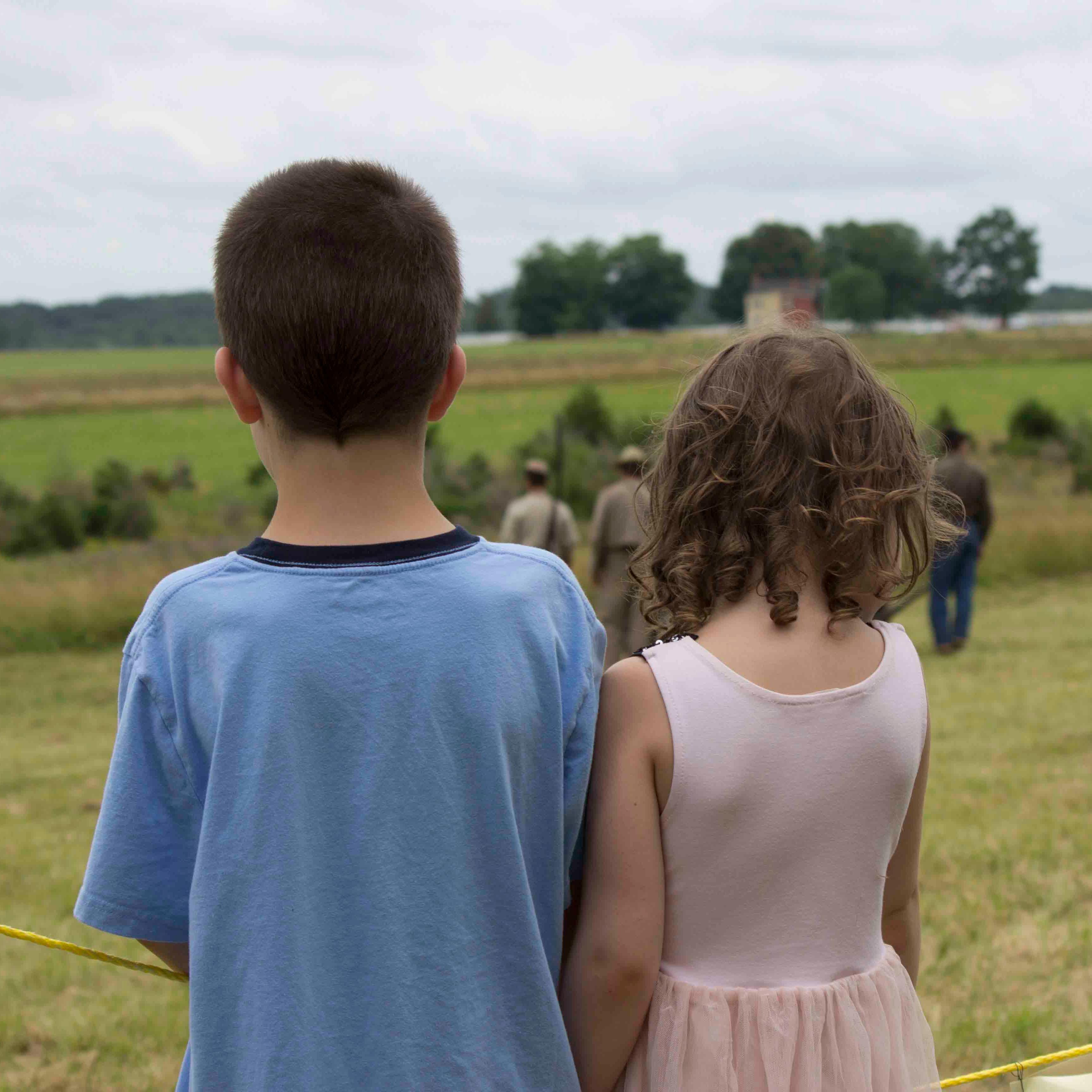A boy and a girl watch an artillery living history demonstration. 