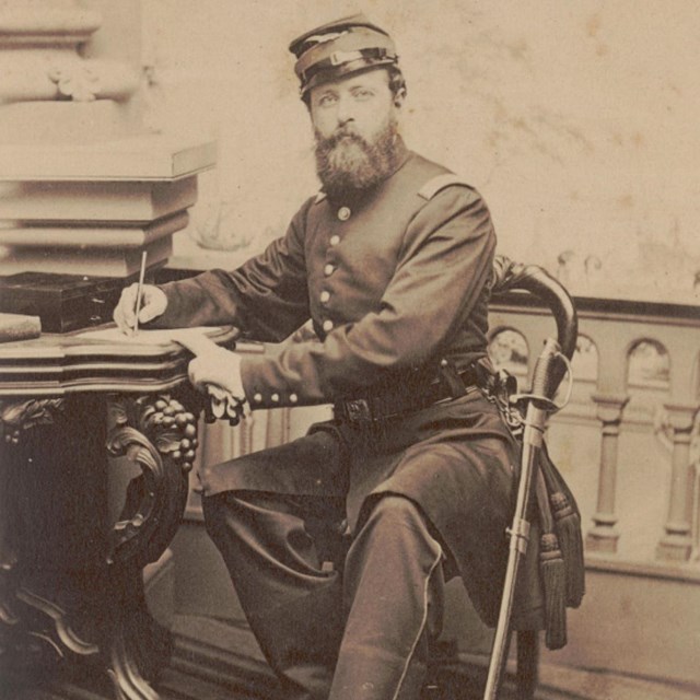 A U.S. soldier sits at a desk with a pen in his hand