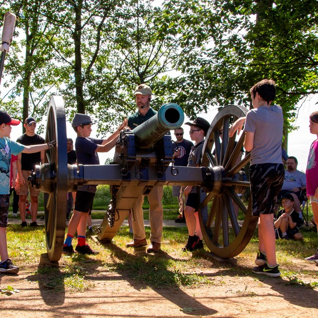 A park volunteer instructs children on the roles of Civil War artillery soldiers.