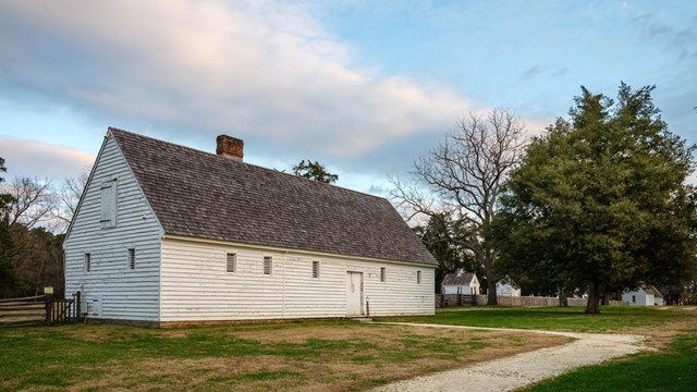 A white barn with a white gravel path leading to the entrance.