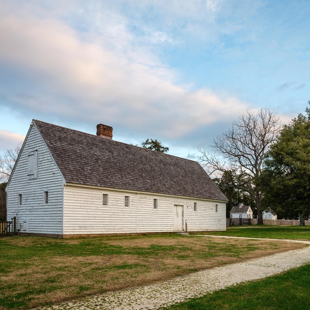 A white barn with a white gravel path leading to the entrance.