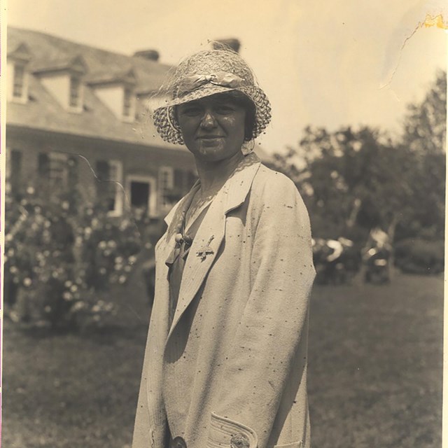 sepia photograph of a woman in a hat and a trench coat standing in Memorial Area