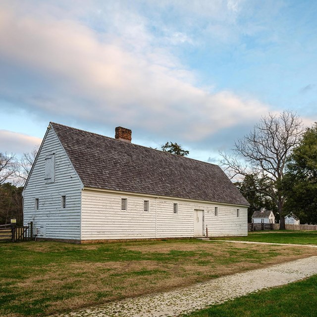 A white barn with a white gravel path leading to the entrance.