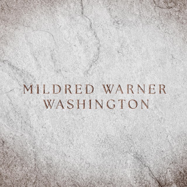 A stone slab with text engraved reads, 