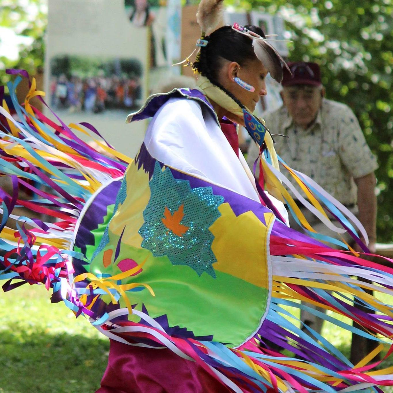 indigenous person in colorful regalia dancing in the memorial area of the park