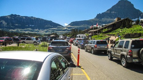 A parking lot outside a visitor center is packed with waiting and parked cars. 