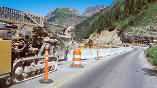 construction vehicles and safety cones on mountain road
