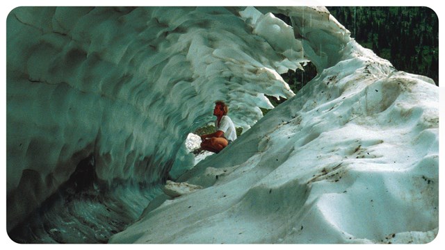 a person crouches inside an ice cave