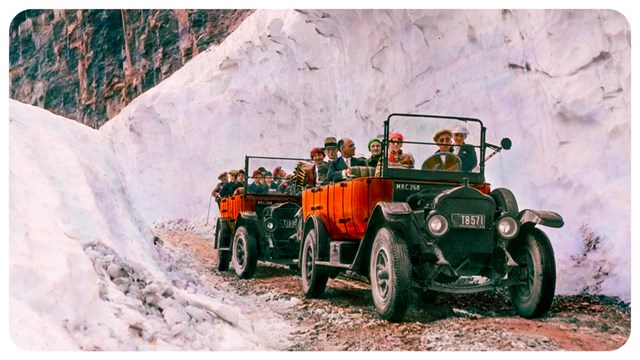 two red buses drive through deep snow with people in back