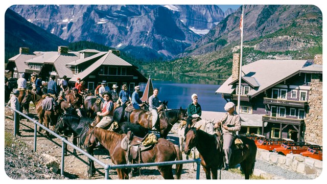 A small group of people sit on a hill with a mountain peak in the background. 