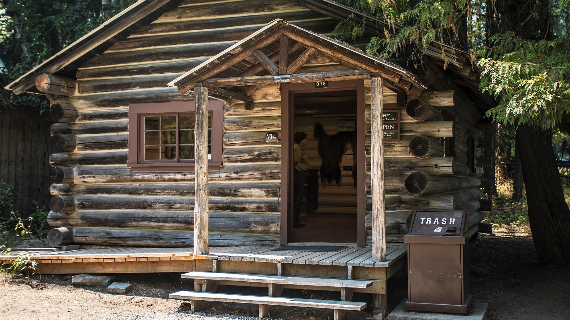 View of a rustic log cabin with its door open.