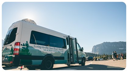 A shuttle bus with sun flaring behind it.