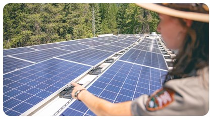 A park ranger points to solar panels. 