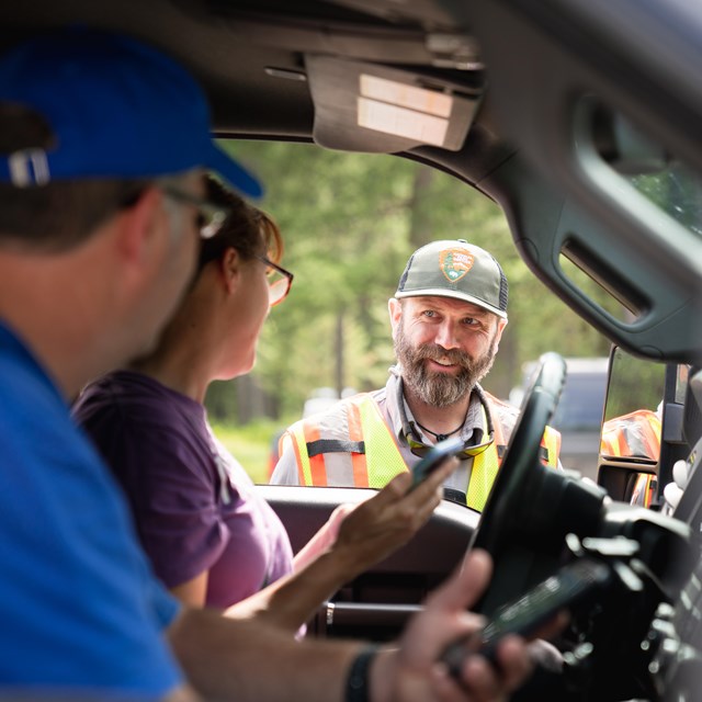 Man talking to travelers through vehicle window.