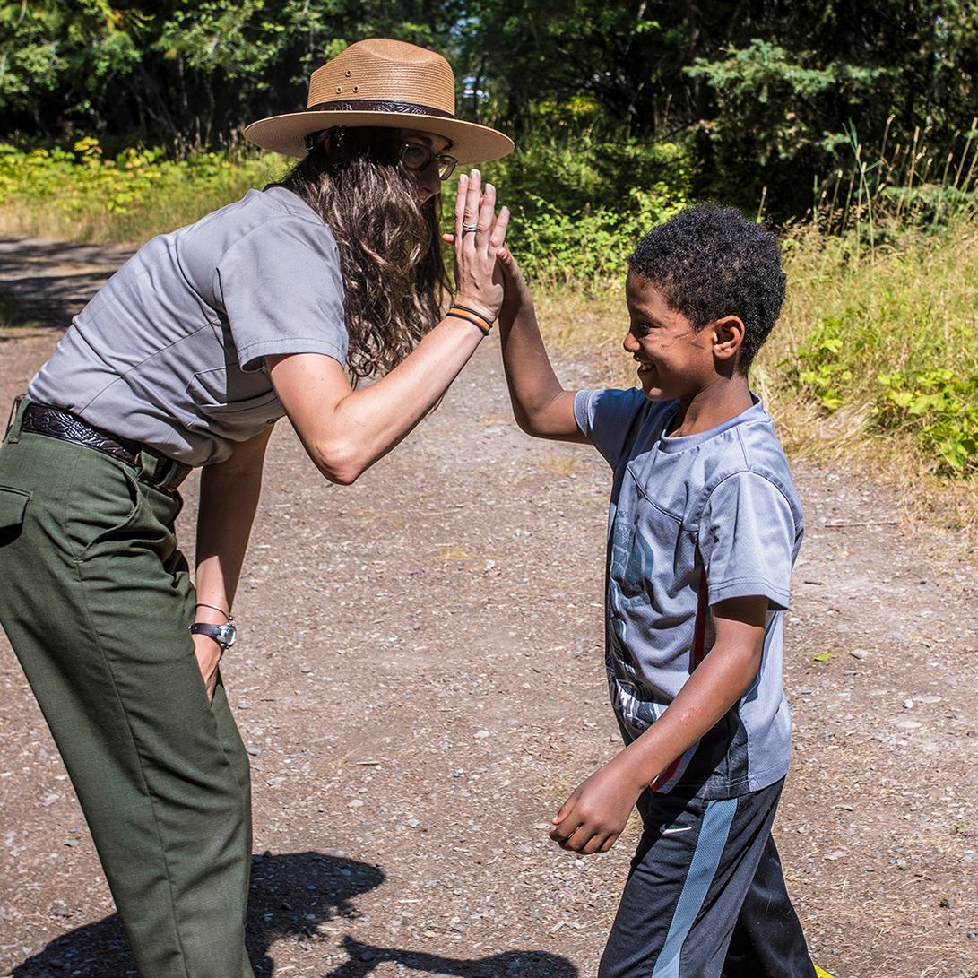 Grinning boy high fives ranger with long curly hair