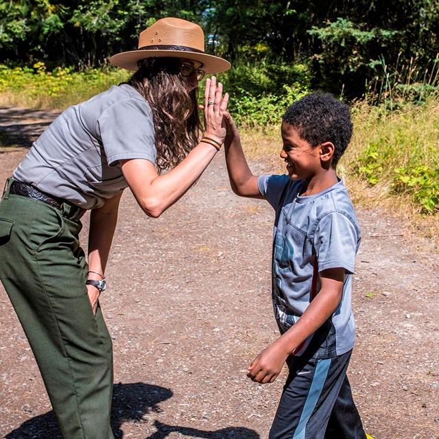 Grinning boy high fives ranger with long curly hair