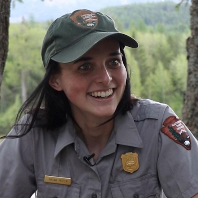 A ranger sits at a picnic table and smiles.