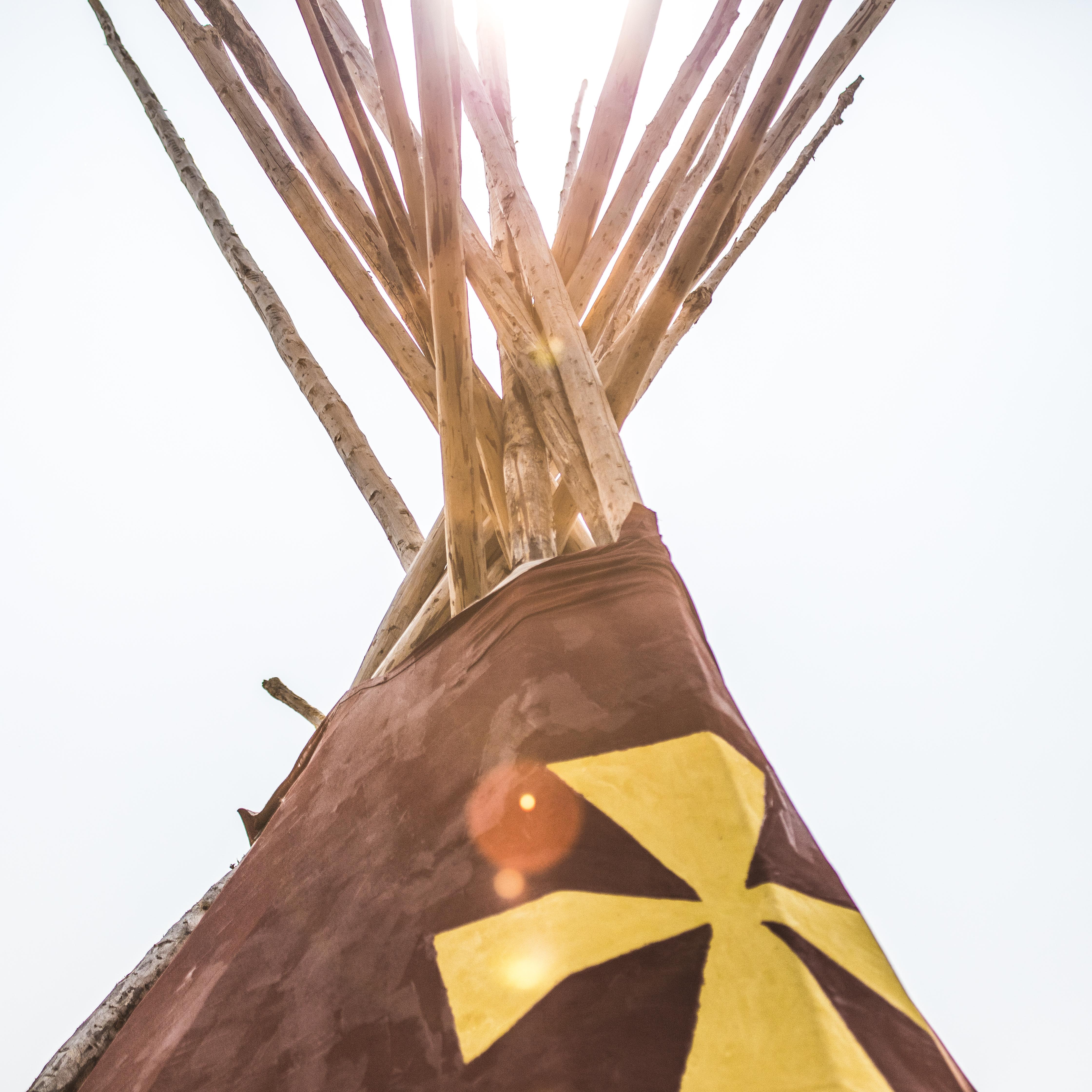 The top of a Blackfeet lodge is highlighted by the sun.